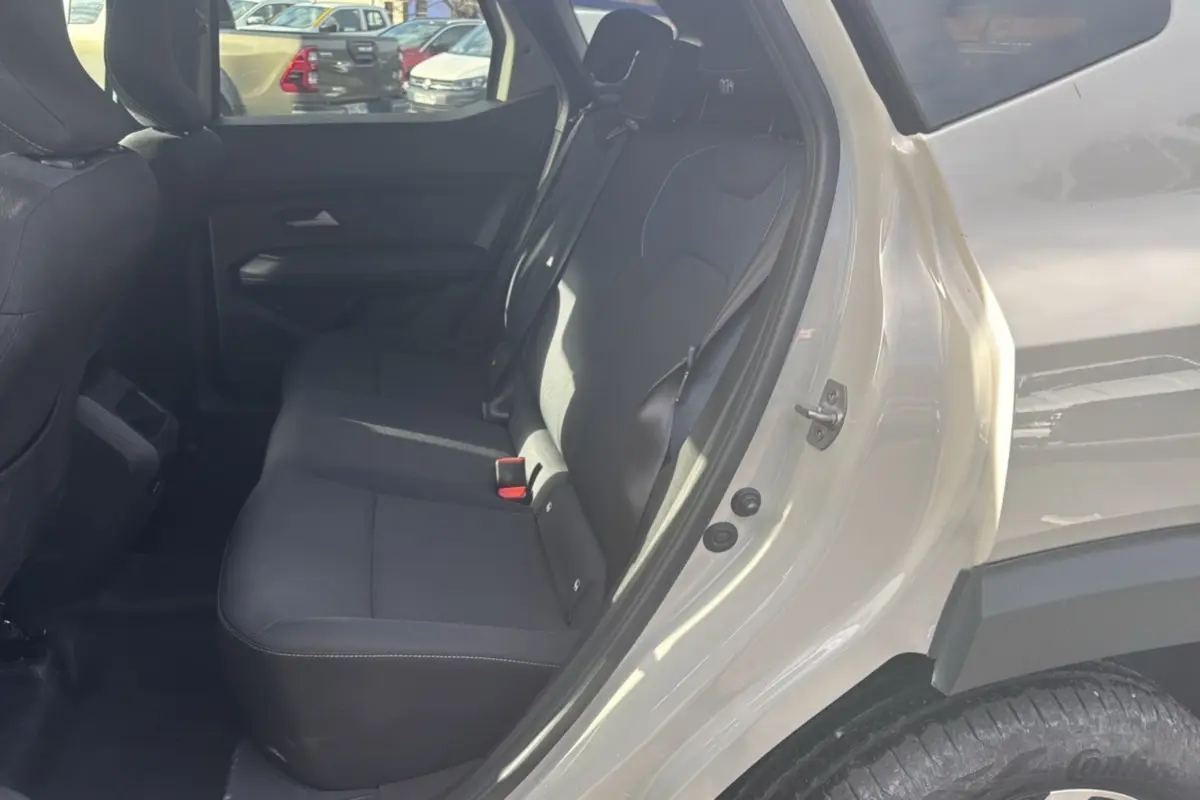 Vue côté droit de l'habitacle arrière du Dacia Duster 2025 Sandstone, montrant la banquette noire et la porte ouverte.