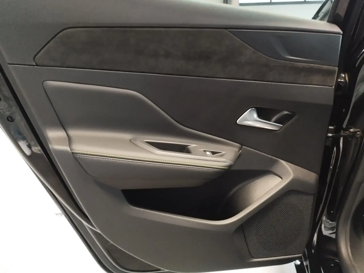 Porte arrière droite ouverte de la Peugeot 308 noire, avec garniture noire et surpiqûres vert Adamite visibles.