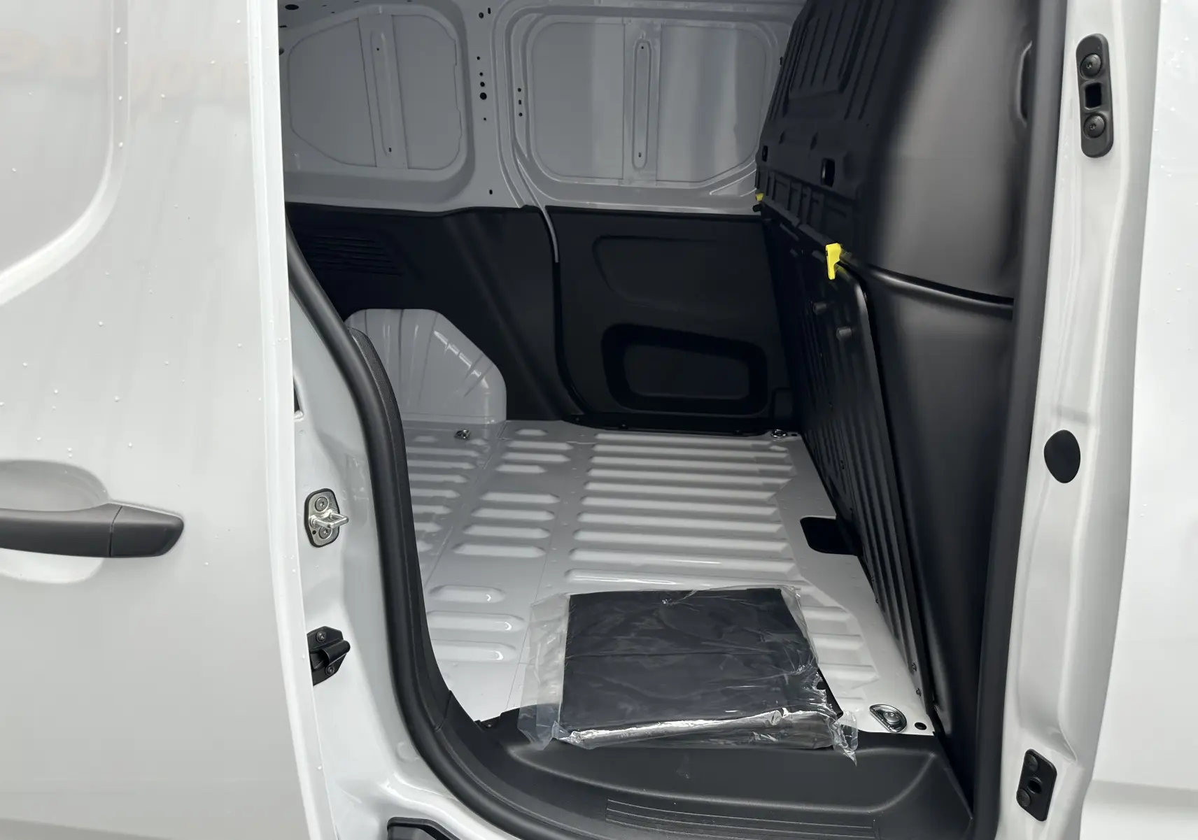 Intérieur du fourgon blanc Peugeot Partner BlueHDi 100ch M 2024 vu côté droit, montrant l'espace de chargement vide.