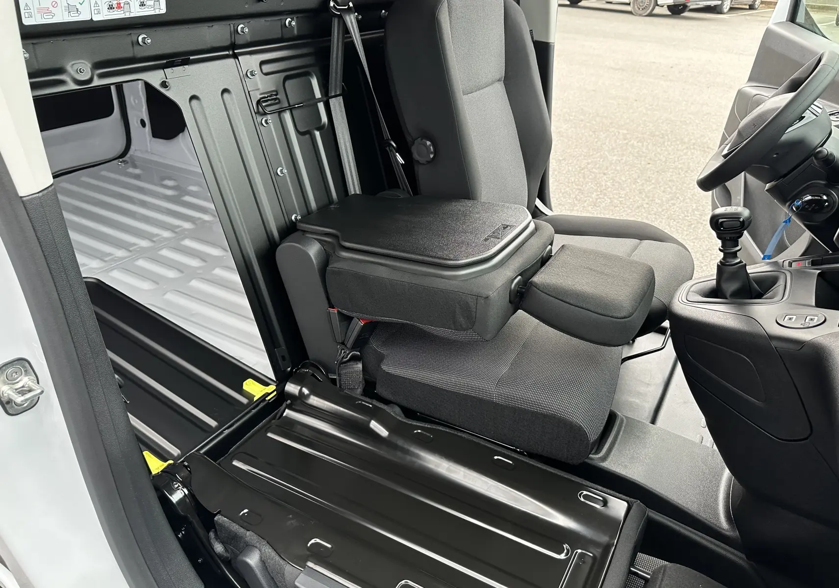 Vue intérieure côté droit du Peugeot Partner Fourgon blanc 2024, montrant le siège passager avec tablette rabattable et plancher utilitaire.
