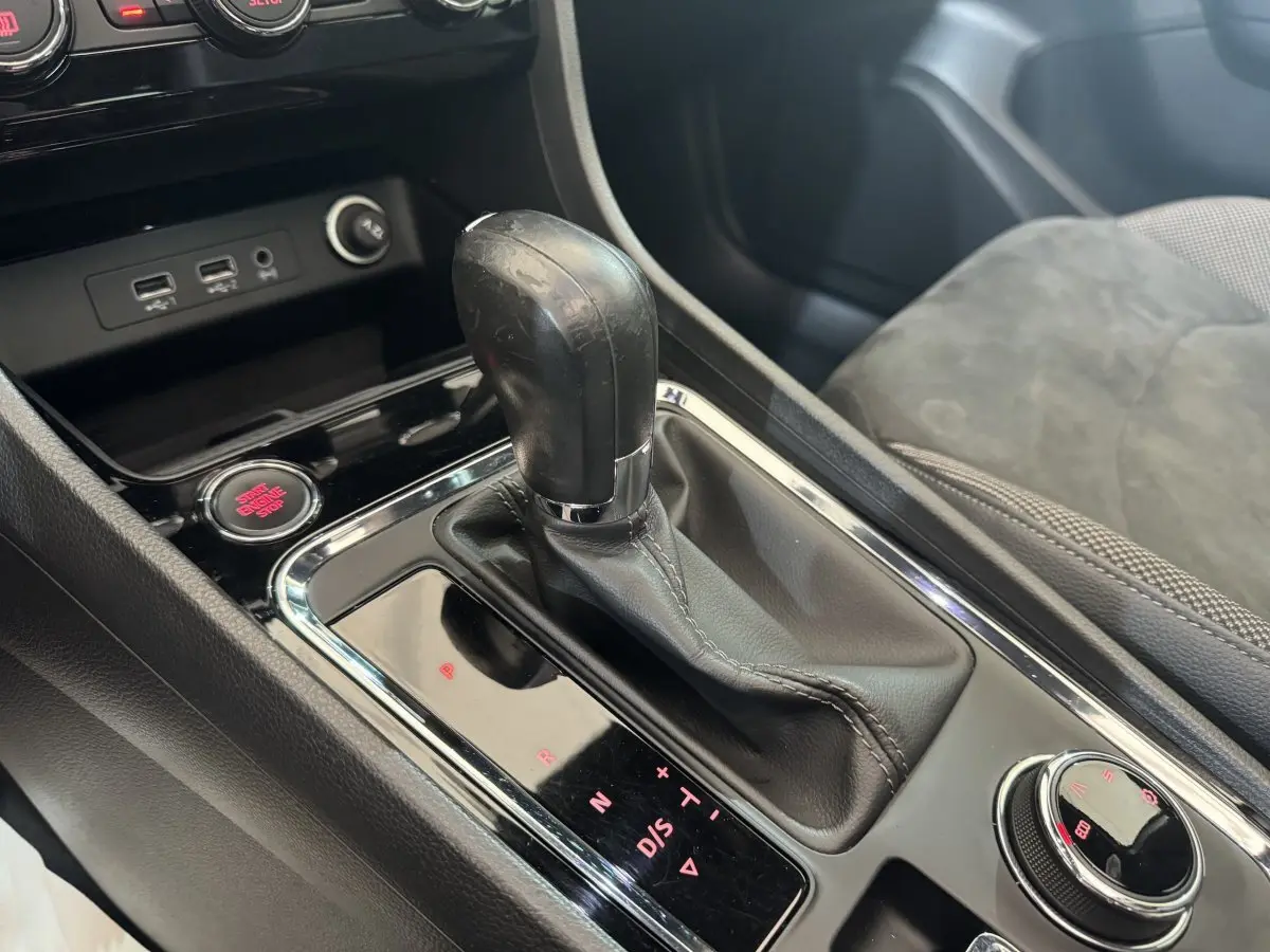 Gros plan sur la console centrale de la SEAT Ateca gris clair, mettant en valeur le levier de vitesses automatique et le bouton start-stop rouge.