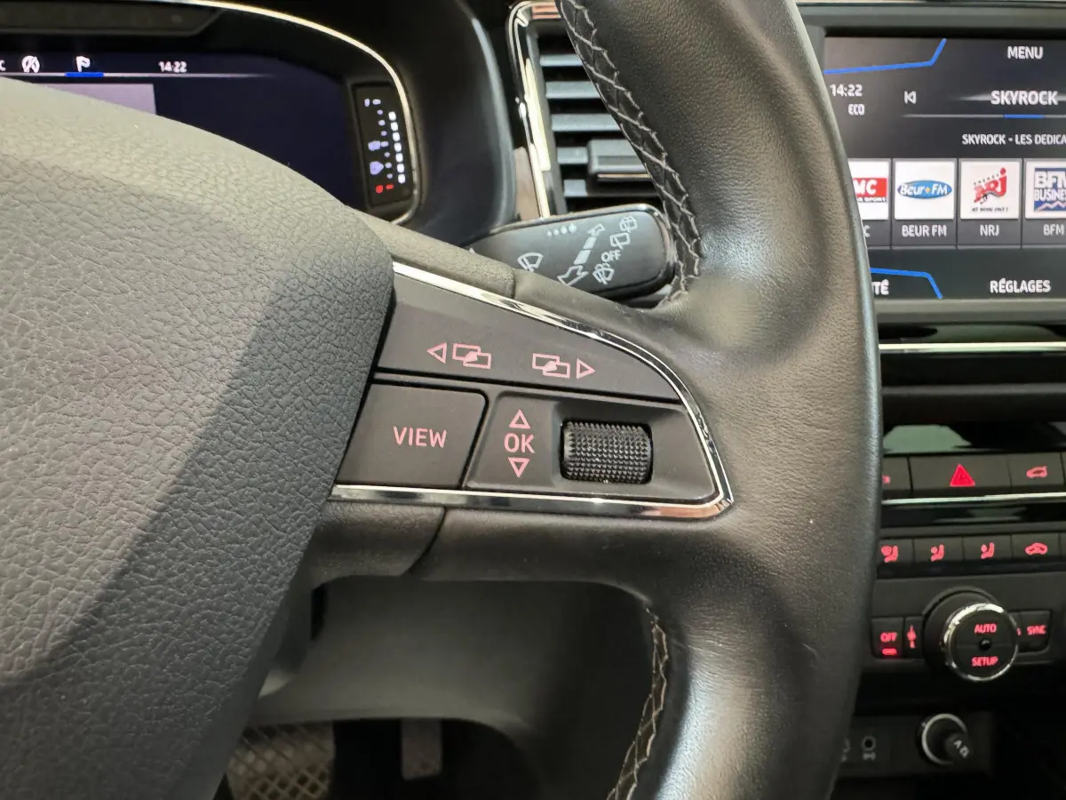 Gros plan sur le volant cuir noir de la SEAT Ateca 2019 avec commandes intégrées et écran tactile en arrière-plan
