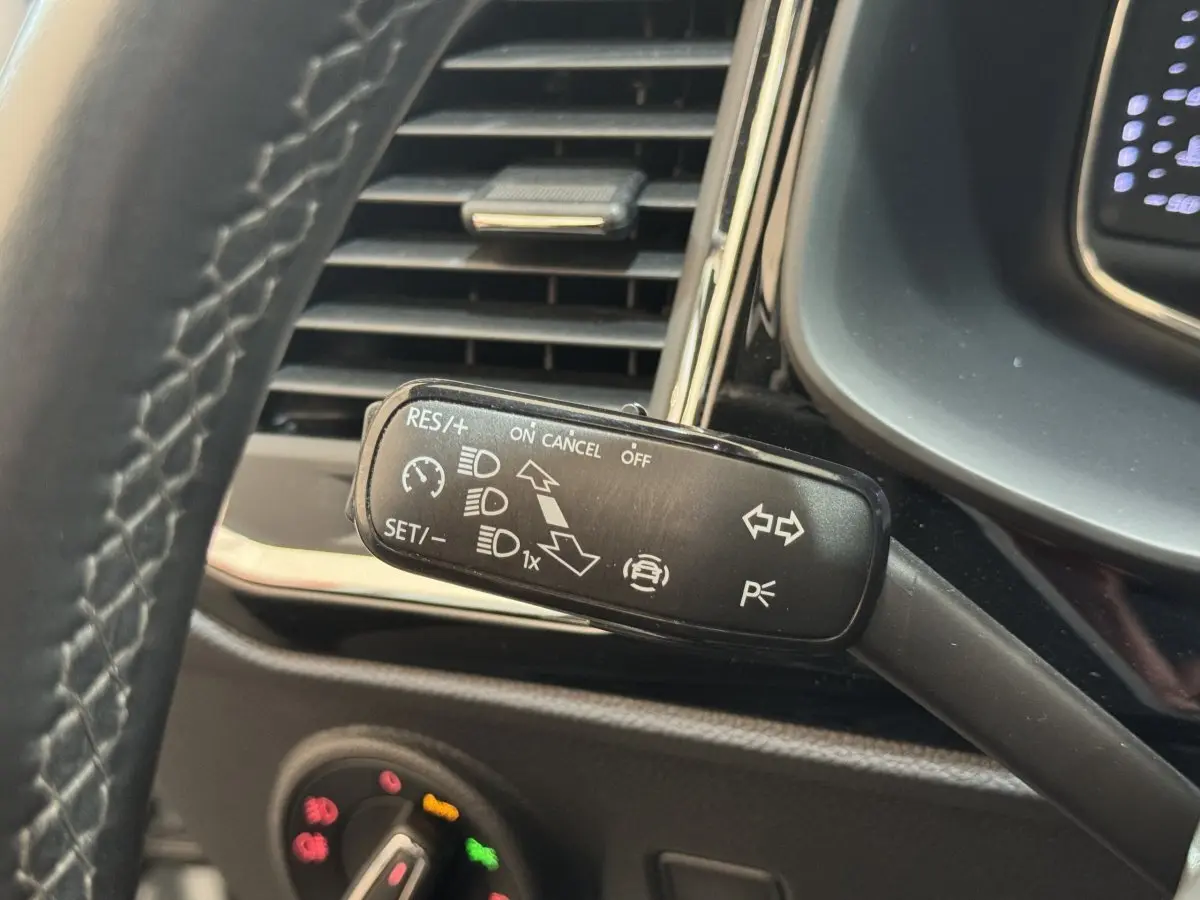 Gros plan sur la commande multifonction noire du régulateur de vitesse, tableau de bord partiel du SEAT Ateca gris clair.