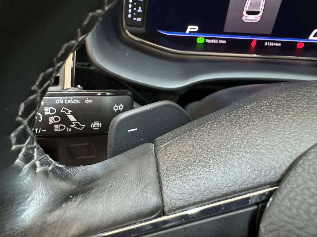 Gros plan sur le volant cuir et la palette de changement de vitesse d'une SEAT Ateca gris clair, tableau de bord numérique visible.