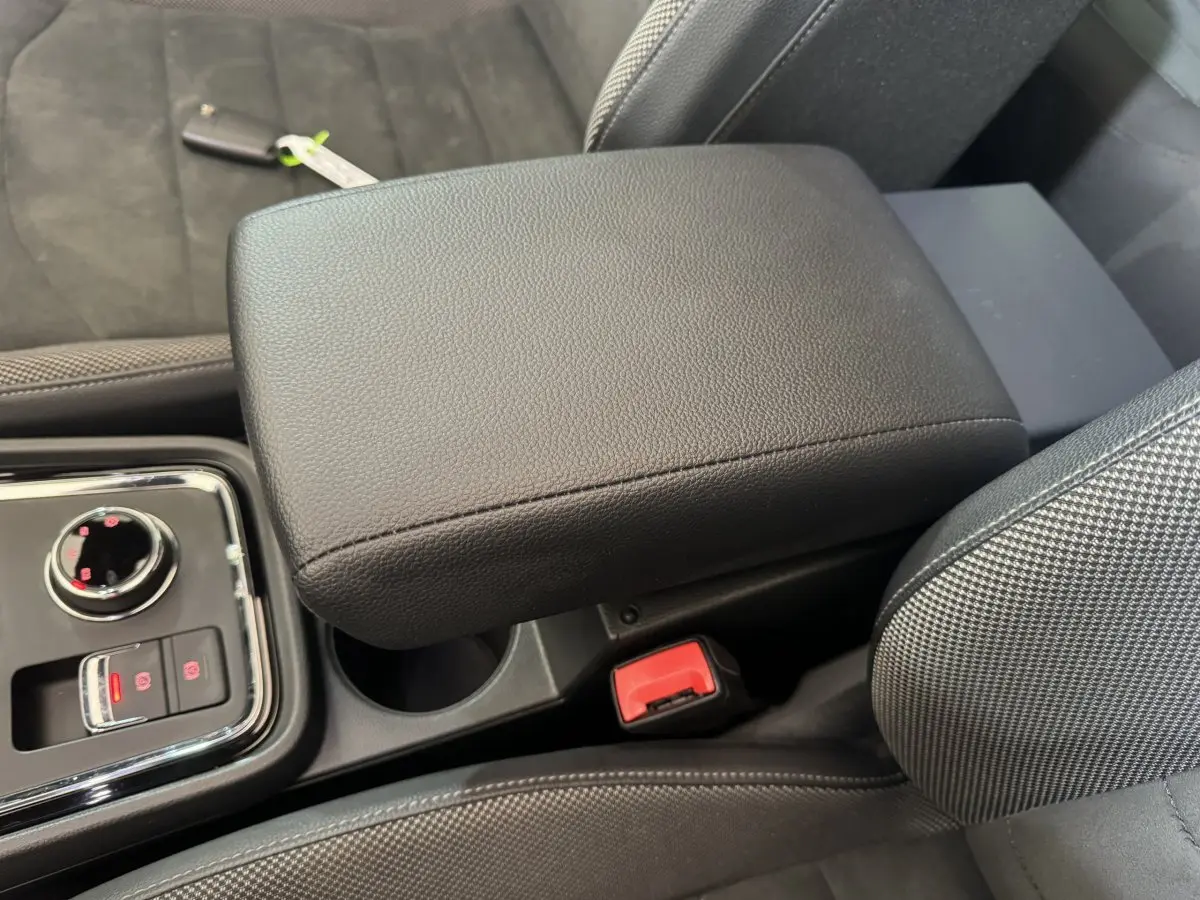 Détail de l'accoudoir central noir et console avec commandes électroniques dans l'habitacle du SEAT Ateca gris clair.