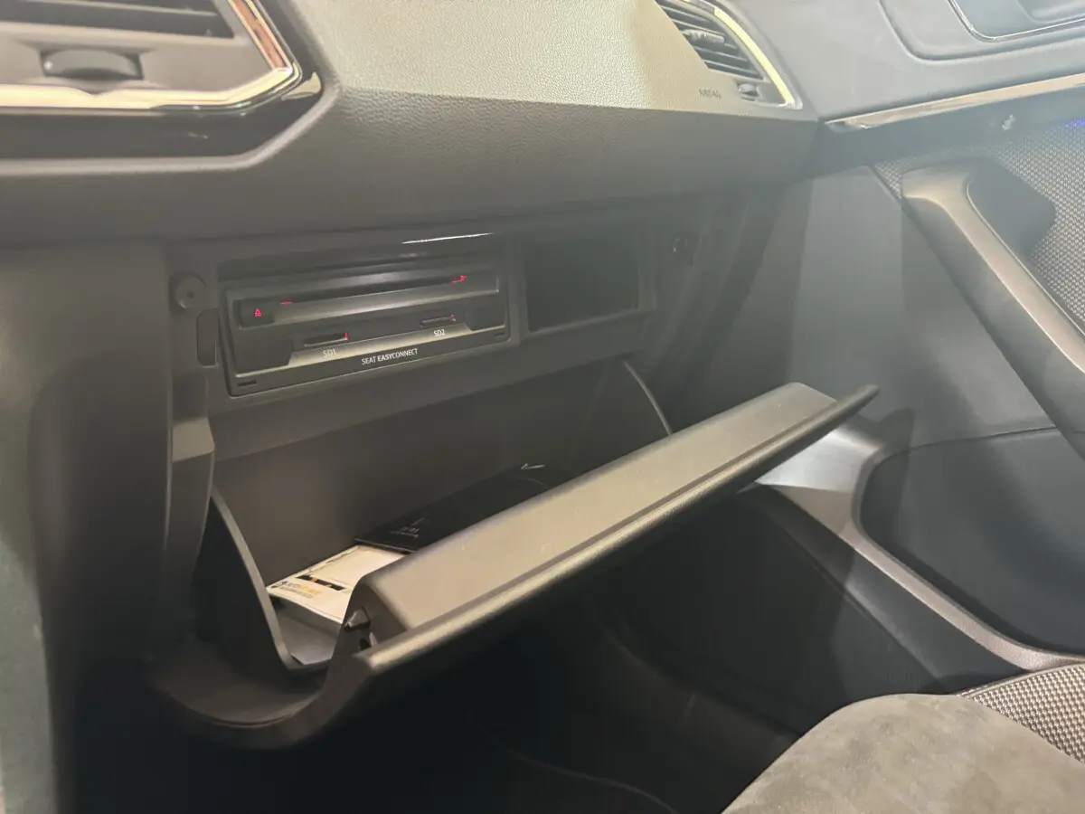 Ouverture de la boîte à gants côté passager dans l'habitacle noir du SEAT Ateca gris clair 2019.