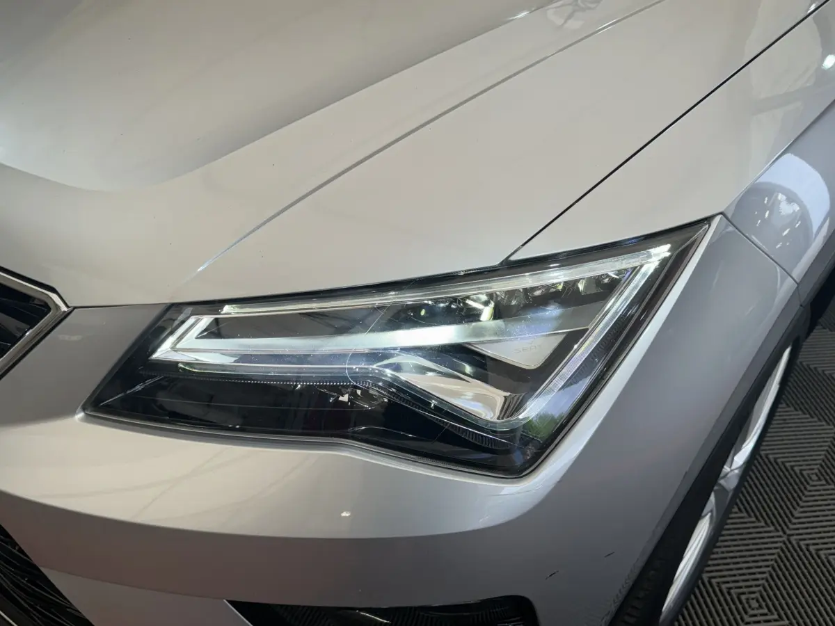 Gros plan sur le phare avant droit d’un SEAT Ateca gris clair, soulignant ses lignes modernes et précises.