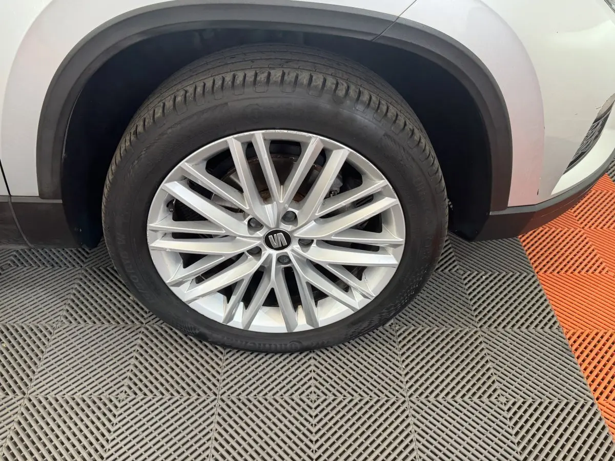 Gros plan sur la roue avant gauche d'un SEAT Ateca gris clair avec jante alliage multi-branches élégante.