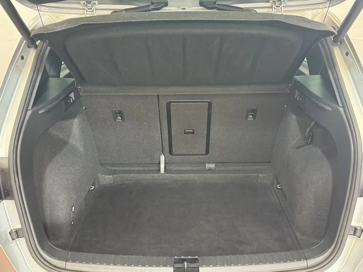 Coffre ouvert d'un SEAT Ateca gris clair, vue directe de l'espace de rangement arrière, intérieur tapissé noir.