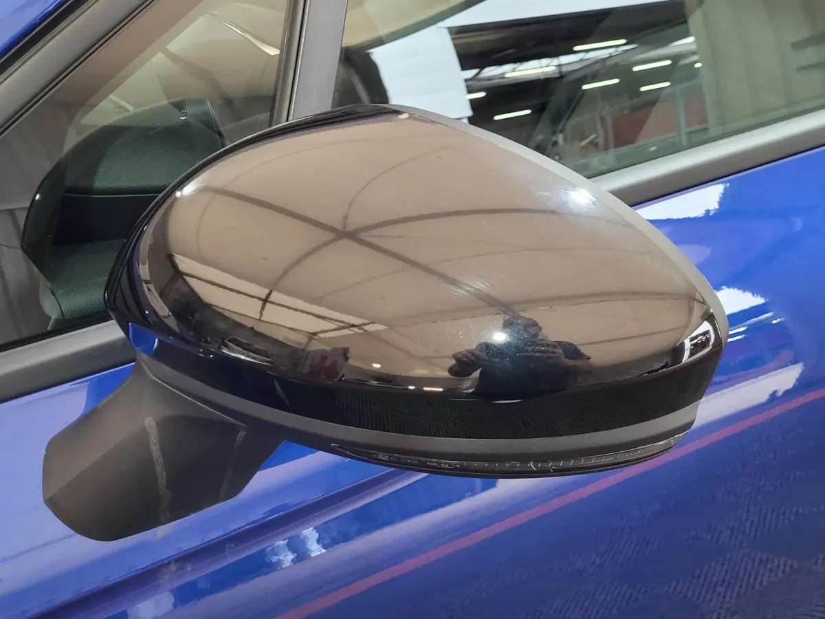 Rétroviseur droit noir brillant sur portière bleu vif d'une Renault Clio Evolution Blue dCi 100 -25 vue de près.