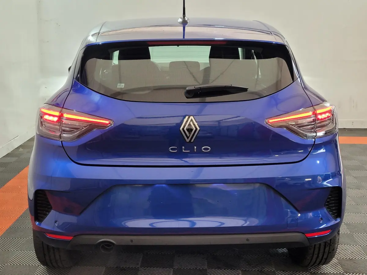 Vue arrière d'une Renault Clio bleu électrique avec feux LED allumés dans un garage.