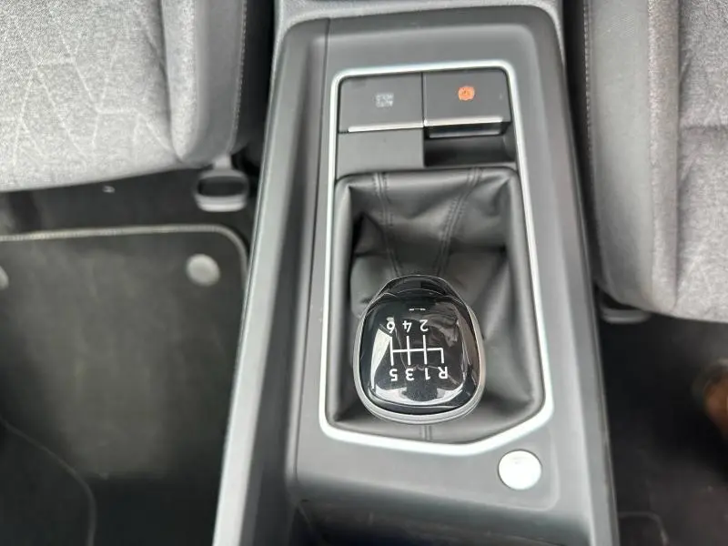 Gros plan sur le levier de vitesse manuel noir et cuir de la Volkswagen Golf 2024, entouré de la console centrale grise.