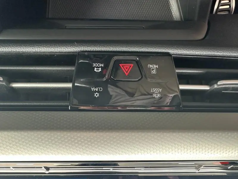 Gros plan sur les commandes centrales noires avec bouton de warning rouge, dans l'habitacle d'une Volkswagen Golf noire.