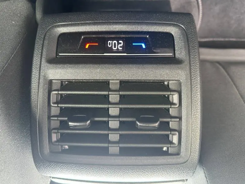 Vue rapprochée des aérateurs arrière avec réglage de la climatisation numérique dans une Volkswagen Golf noire intense nacrée 2024.