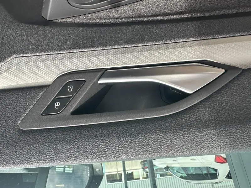 Poignée intérieure côté gauche de porte avec boutons de verrouillage, finition noire et insert argenté sur Volkswagen Golf 2024.