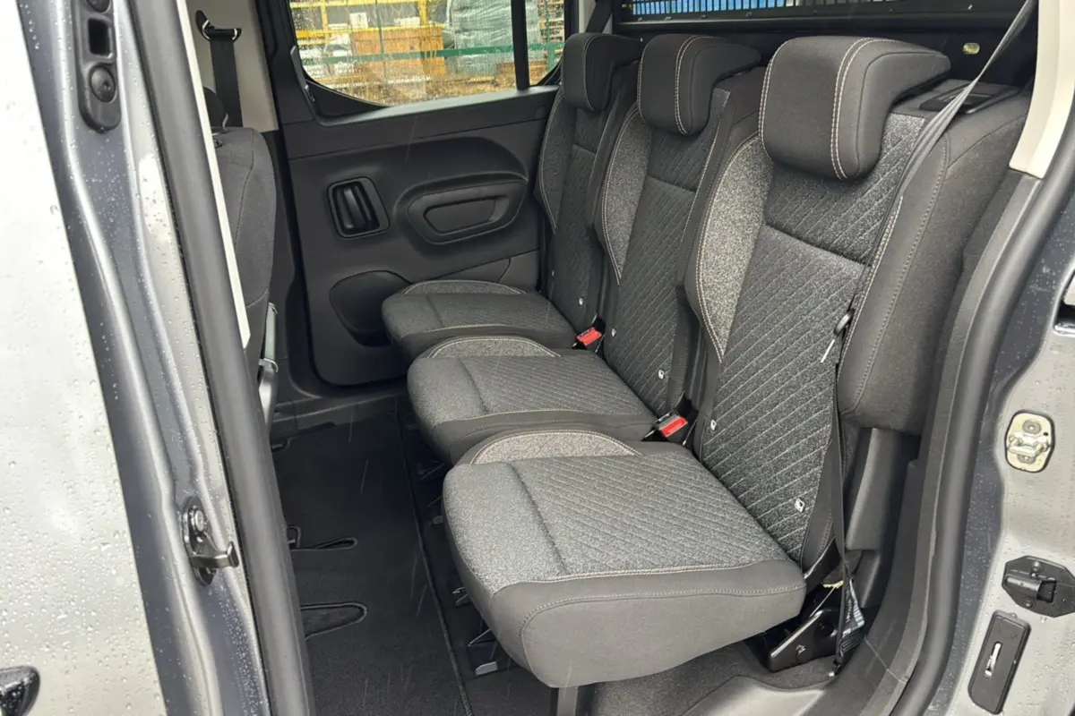 Vue intérieure côté gauche sur la banquette arrière grise tissu du Peugeot Rifter 2026 gris artense avec porte coulissante ouverte.