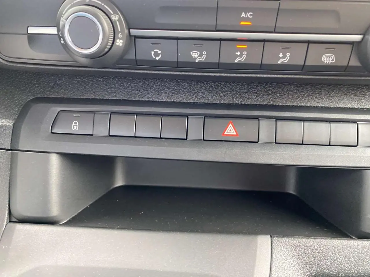 Gros plan sur la console centrale noire du Peugeot Expert Fourgon avec boutons de commande et témoin A/C allumé.
