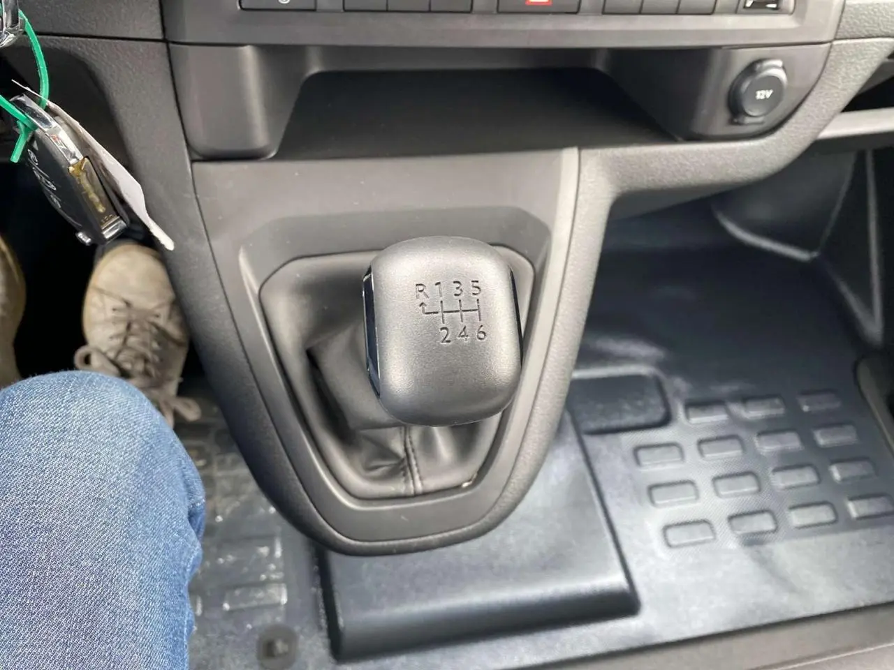 Vue rapprochée du levier de vitesses manuel noir du Peugeot Expert Fourgon blanc 2023, avec plancher caoutchouc visible.