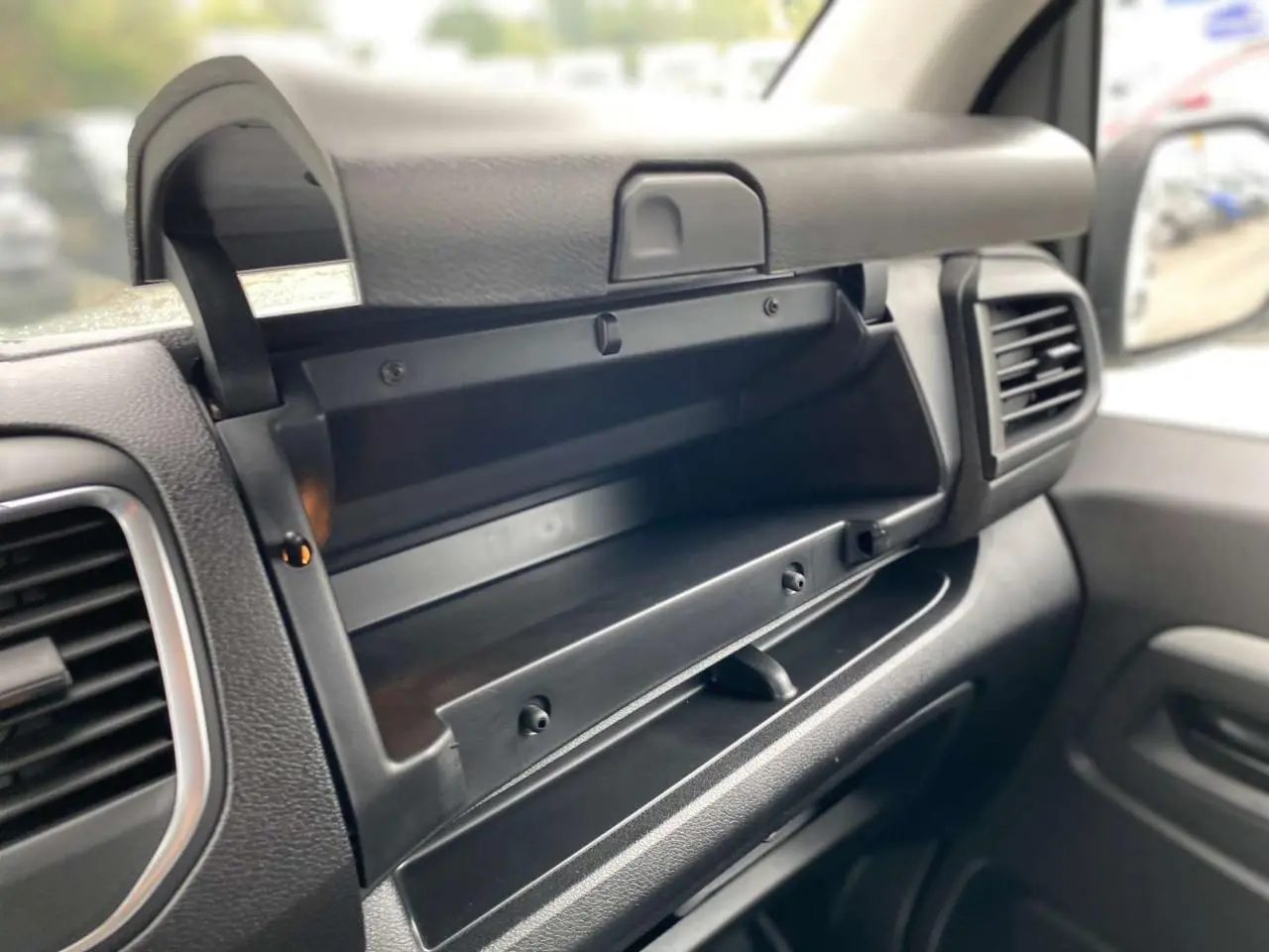 Intérieur du Peugeot Expert Fourgon blanc 2023, vue rapprochée du rangement ouvert côté passager avec tableau de bord noir.