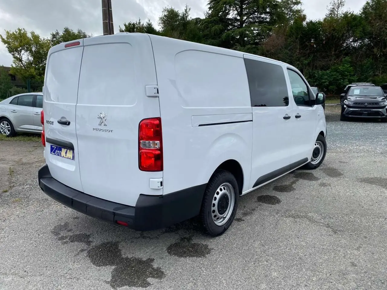 Vue 3/4 arrière droite d'un Peugeot Expert Fourgon blanc avec porte latérale coulissante et feux arrière rouges.