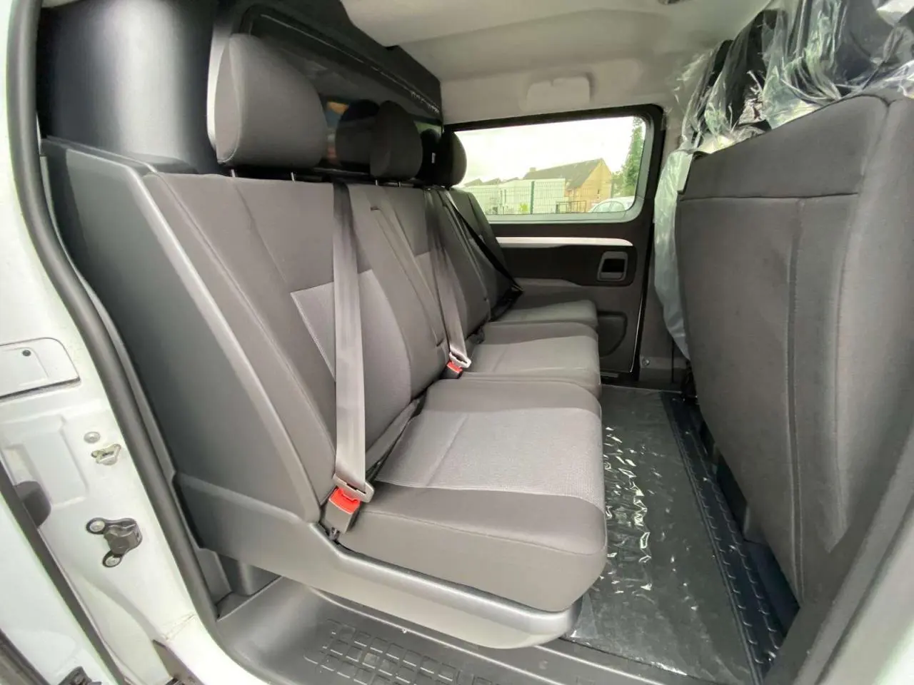 Vue intérieure côté droit du Peugeot Expert Fourgon blanc 2023, banquette arrière grise trois places avec ceintures de sécurité.