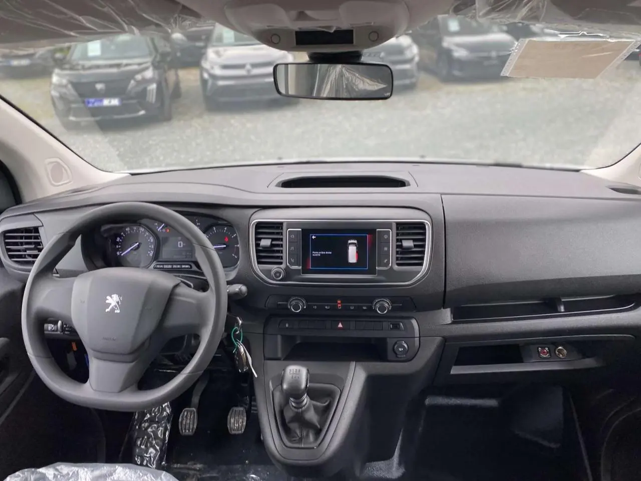 Vue intérieure du tableau de bord du Peugeot Expert Fourgon blanc 2023 avec volant, écran tactile et levier de vitesses manuel.