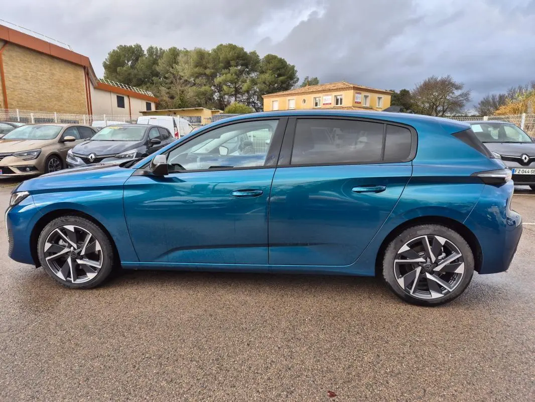 Vue latérale droite d'une Peugeot 308 bleu métallisé 2024 avec jantes alliage 17 pouces et vitres teintées.