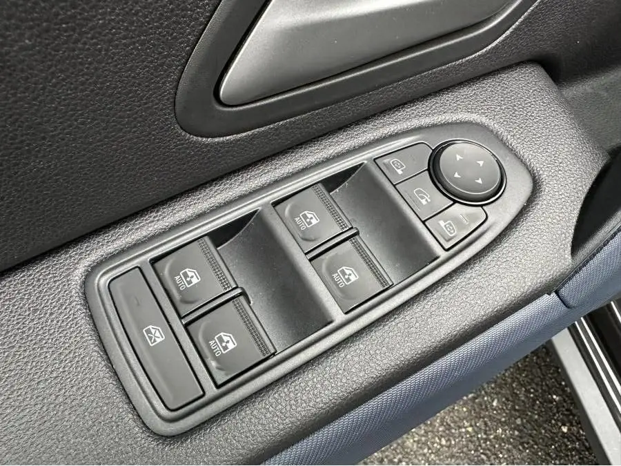 Gros plan sur les commandes des vitres et rétroviseurs côté conducteur du Dacia Duster noir 2025.
