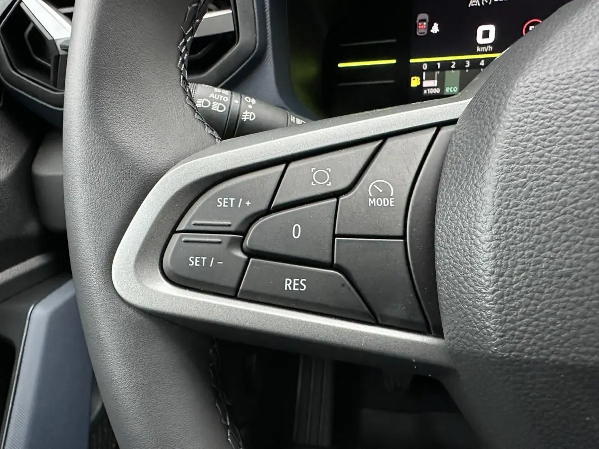 Gros plan sur les commandes de régulateur de vitesse à gauche du volant du Dacia Duster noir 2025.