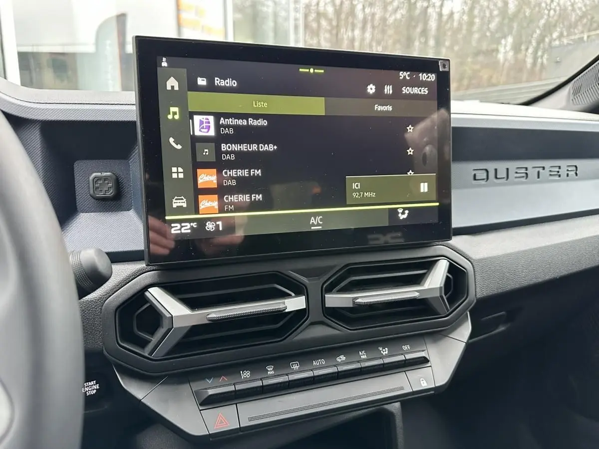 Vue intérieure centrée sur la console centrale du Dacia Duster 2025 avec écran tactile et aérateurs hexagonaux.