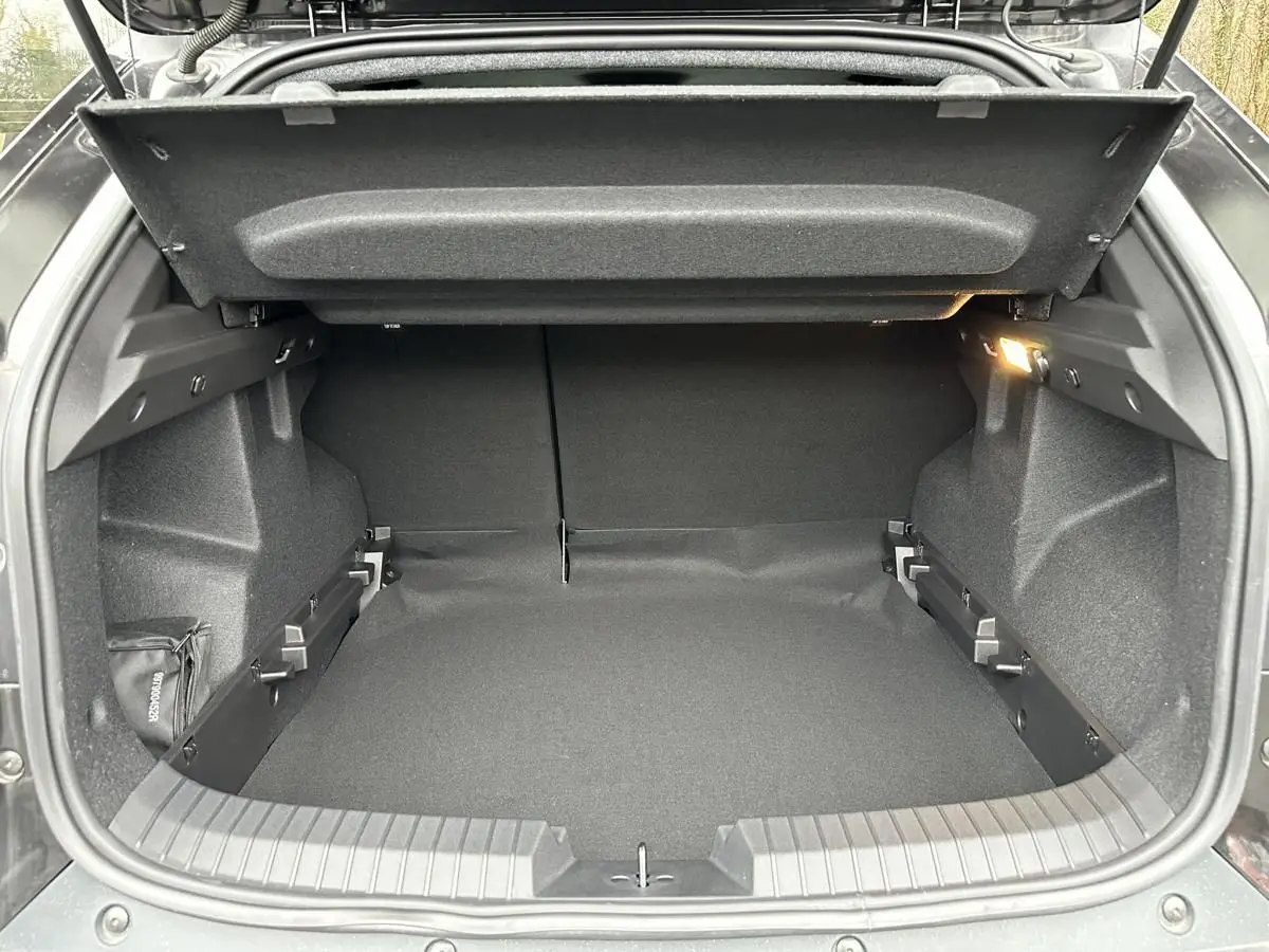 Coffre ouvert du Dacia Duster noir 2025, vue arrière, montrant l’espace de chargement et l’éclairage intérieur.