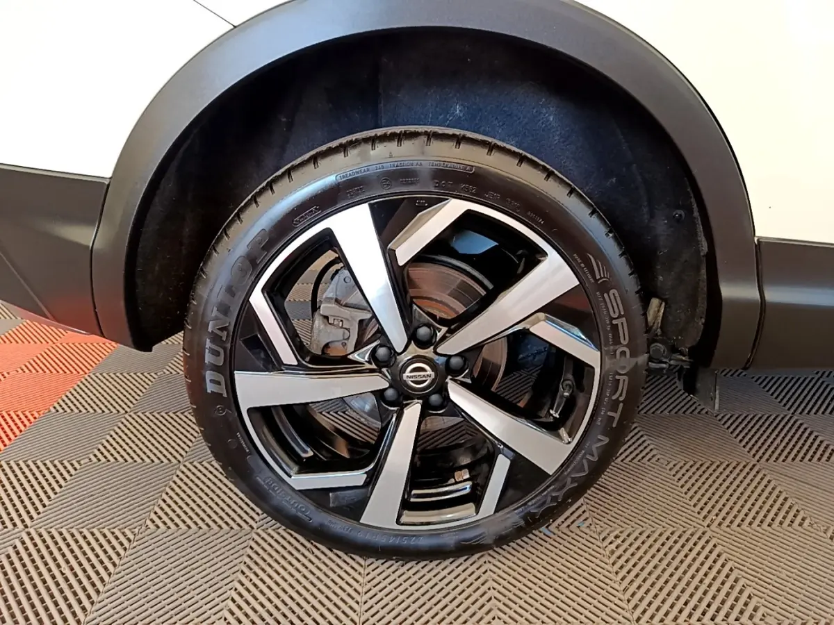 Gros plan sur la roue avant droite du Nissan Qashqai blanc avec jante alliage noire et argentée.