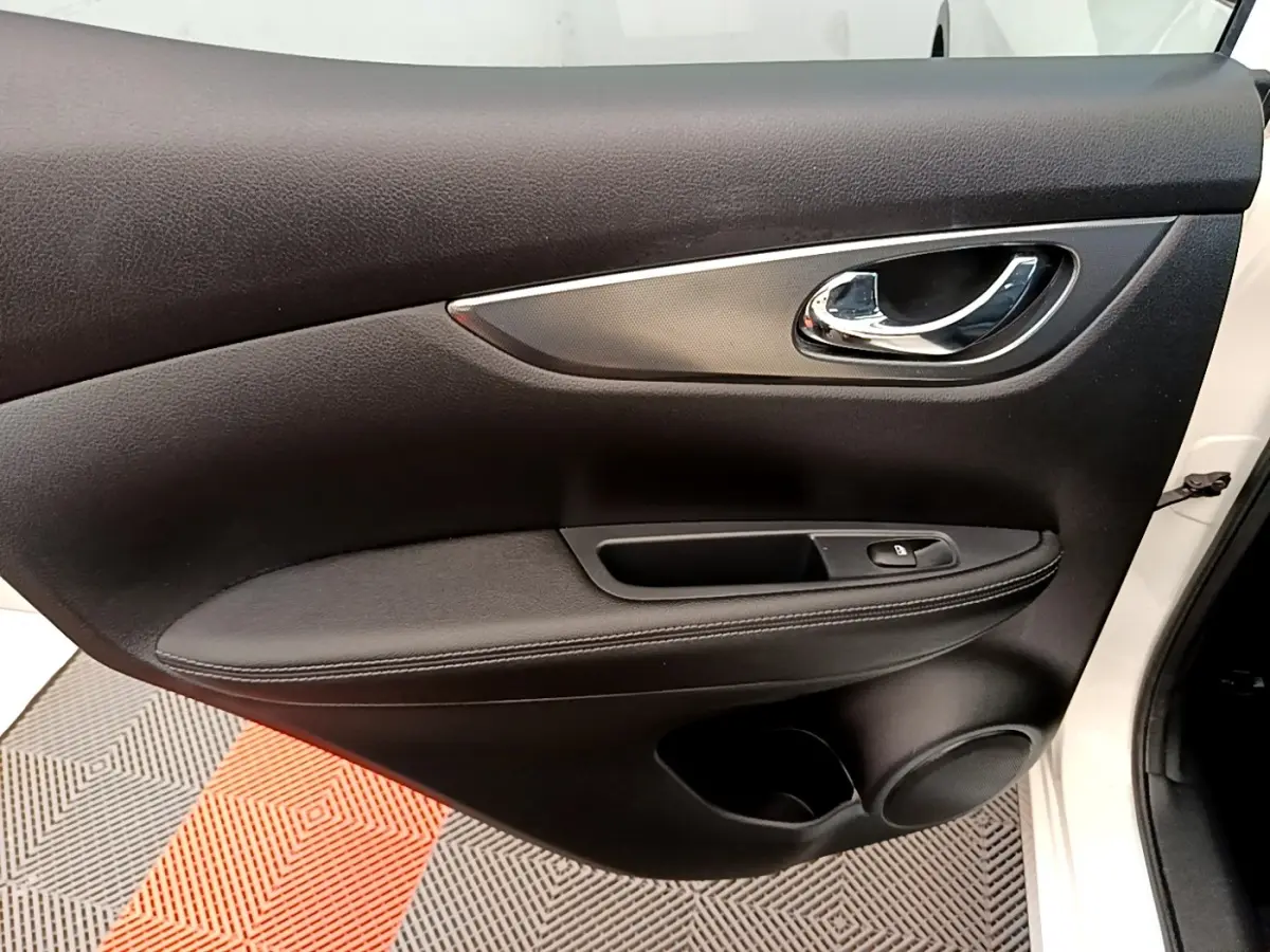 Gros plan sur la porte avant droite noire du Nissan Qashqai blanc, avec poignée chromée et commande de vitre.