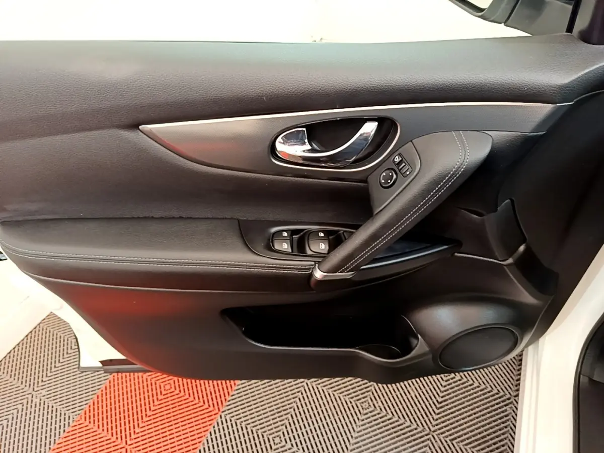 Vue intérieure côté gauche de la porte avant noire du Nissan Qashqai blanc avec commandes de vitres et poignée chromée.