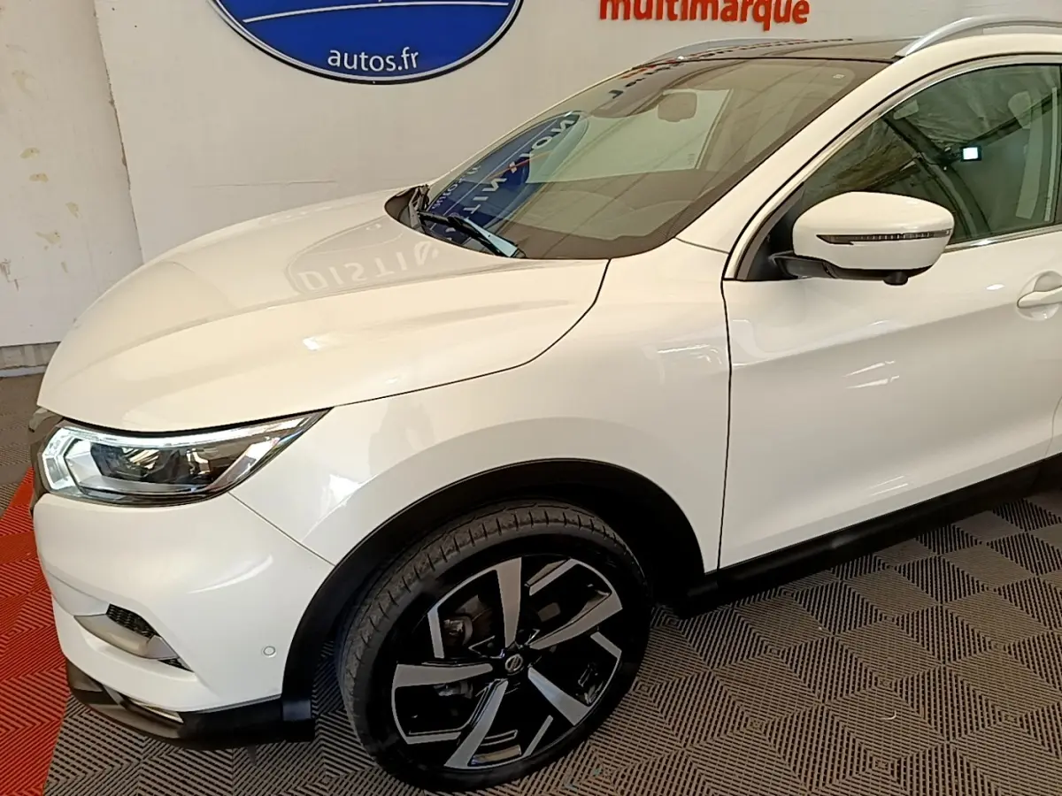 Vue 3/4 avant droit du Nissan Qashqai blanc 2019 avec jantes alliage noires et rétroviseur à clignotant intégré.