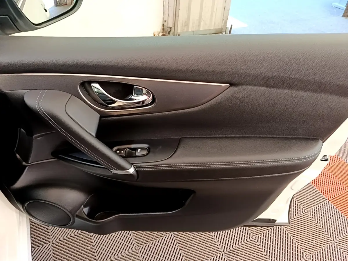 Gros plan sur la porte avant droite noire du Nissan Qashqai blanc, avec poignée chromée et commandes de vitres.
