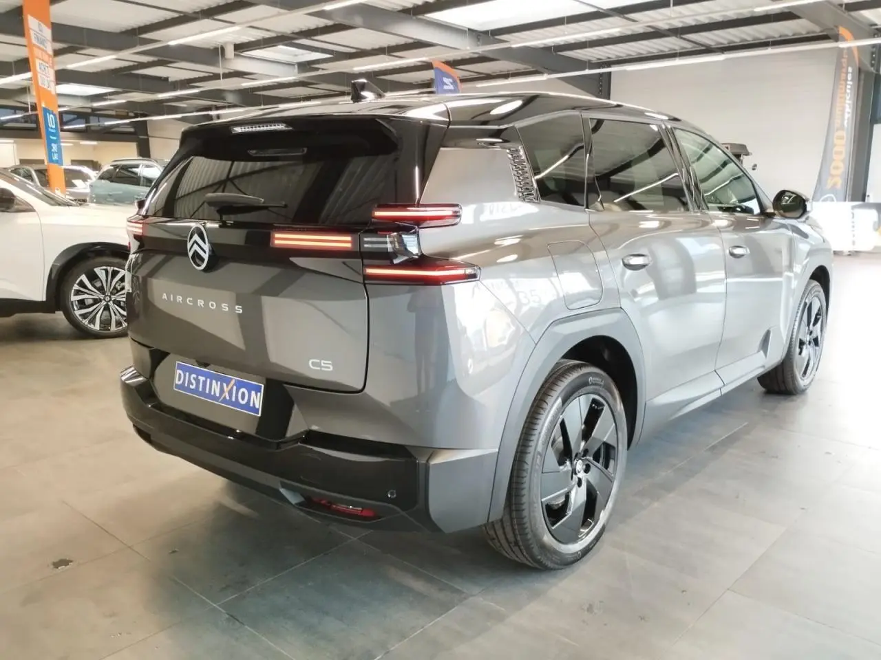 Vue 3/4 arrière droite d'un Citroën C5 Aircross gris platine avec toit noir et jantes alliage noires.