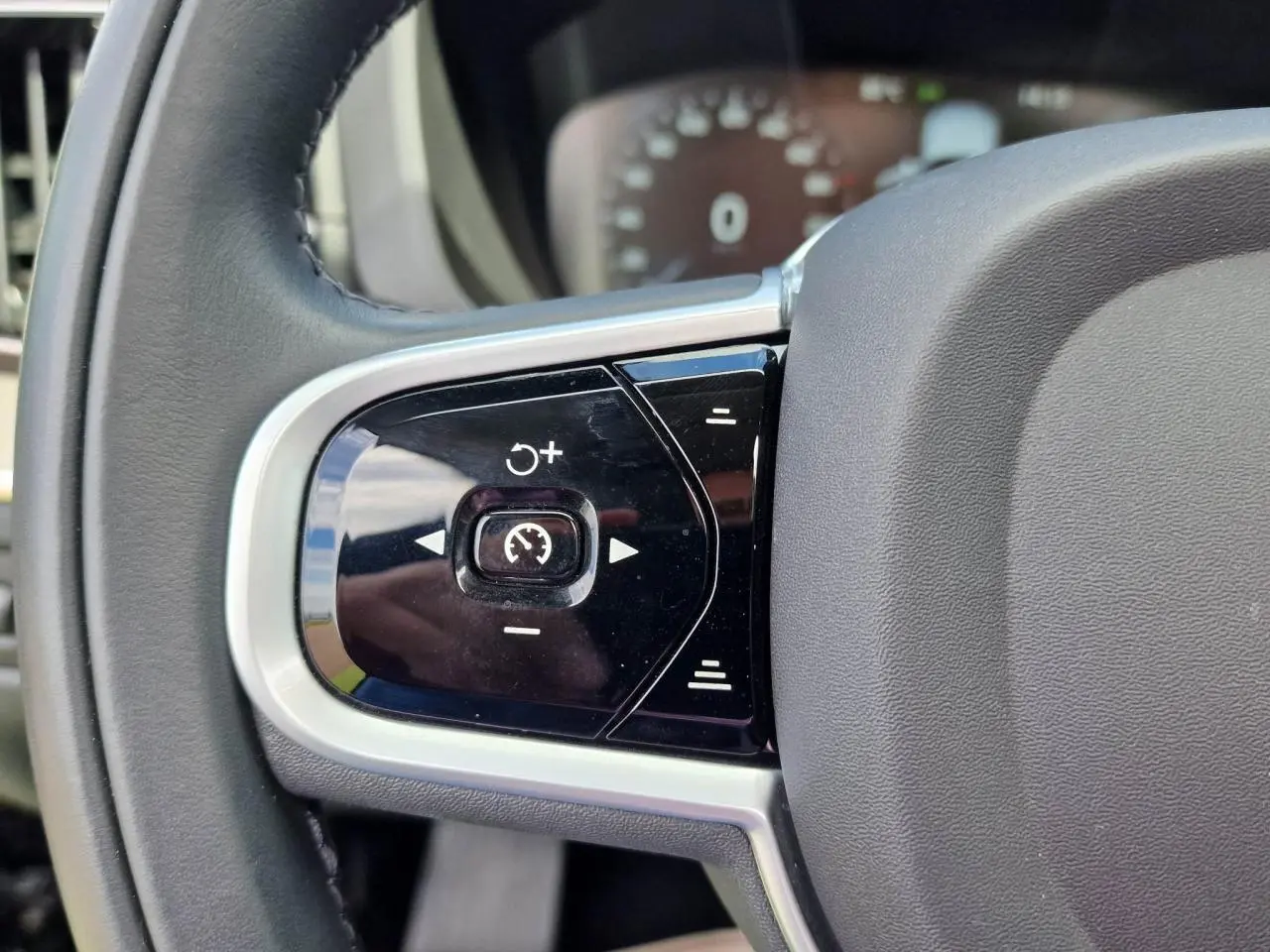 Gros plan sur les commandes de régulateur de vitesse au volant cuir noir du Volvo XC60 II Recharge T6 2021.