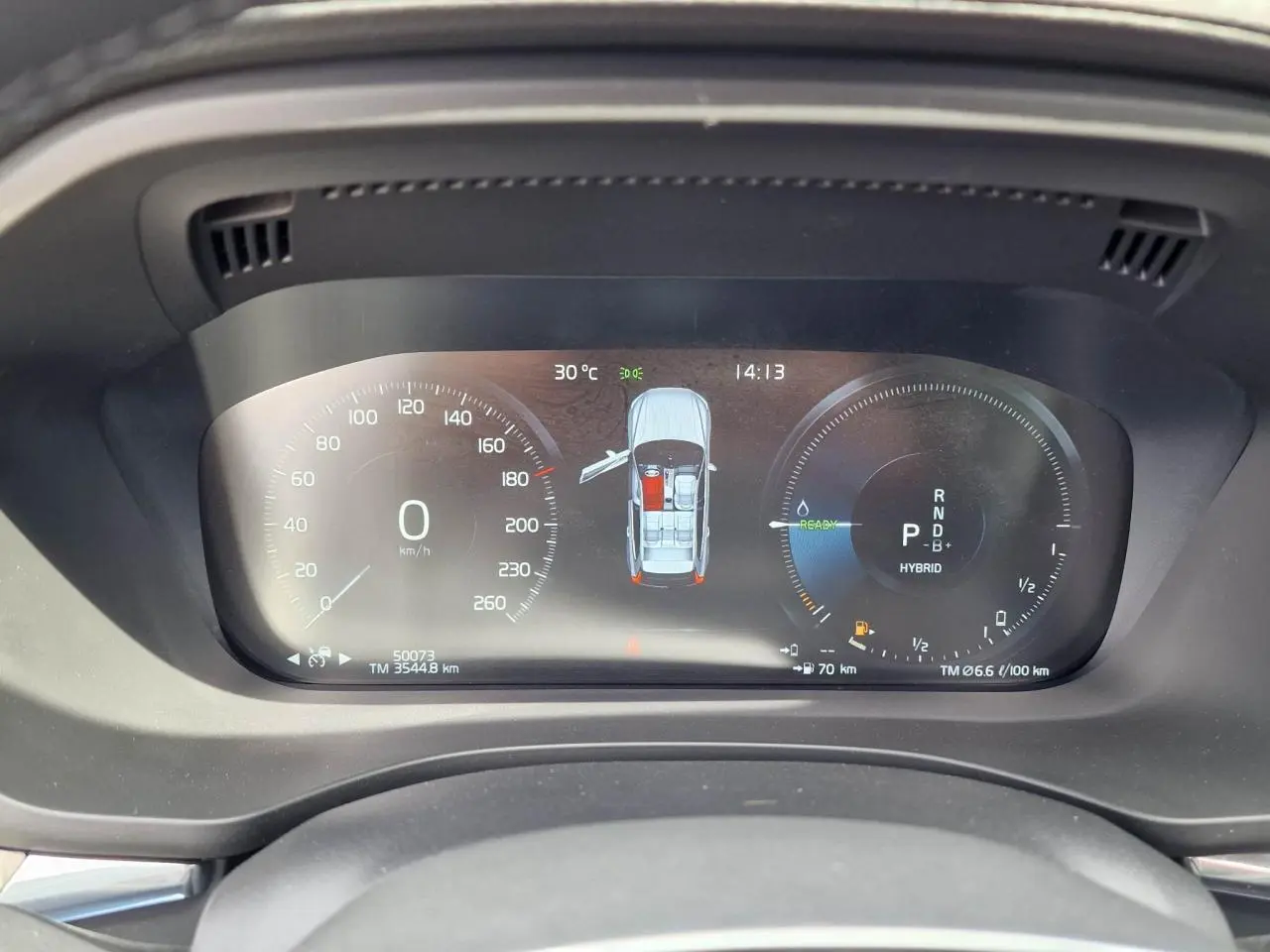 Combiné d'instruments digital du Volvo XC60 noir, affichant vitesse, mode hybride et portes ouvertes, vue de face.