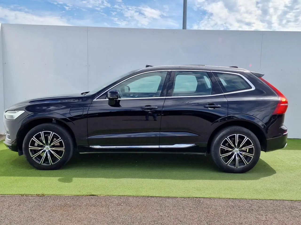 Profil côté gauche du Volvo XC60 noir 2021 avec jantes alliage 19 pouces et toit panoramique visible.