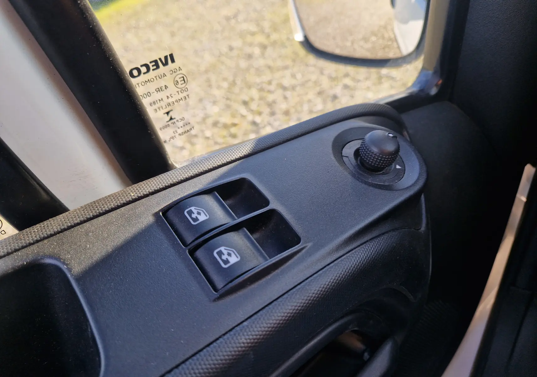 Gros plan sur les commandes de lève-vitres et réglage des rétroviseurs côté gauche d'un Iveco Daily Fourgon blanc 2022.