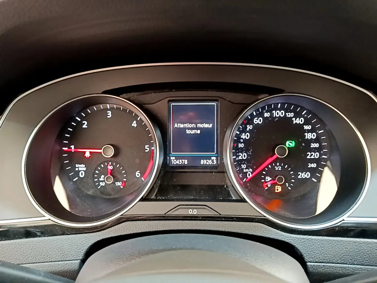 Tableau de bord de Volkswagen Passat gris foncé, affichage digital central avec message moteur et compteurs analogiques.