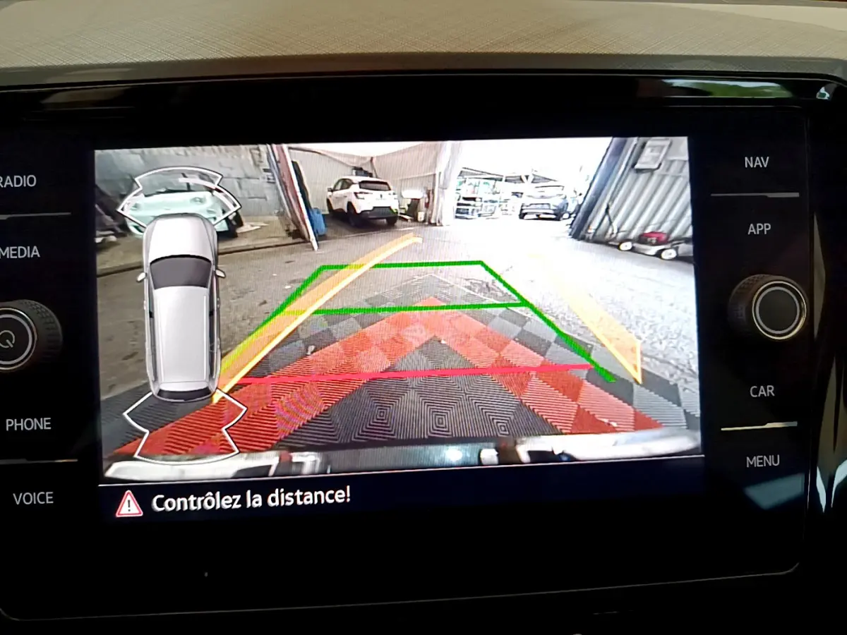 Affichage caméra de recul avec guidage coloré sur écran tactile du tableau de bord d'une Volkswagen Passat gris foncé.