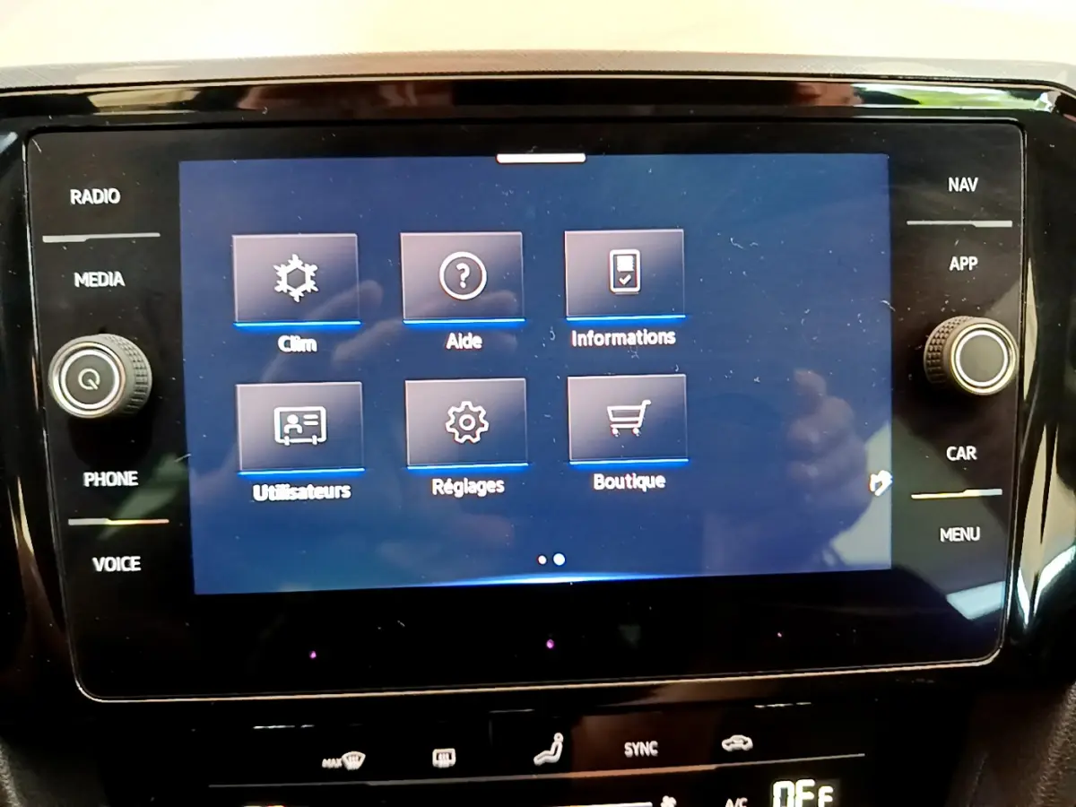 Écran tactile central de la Volkswagen Passat 2021 affichant le menu principal avec options clim, aide et réglages.
