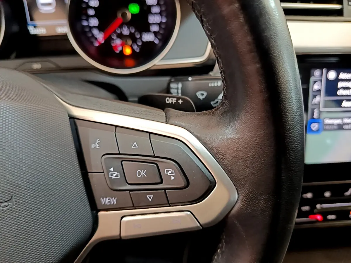 Gros plan sur les commandes multifonctions du volant cuir noir de la Volkswagen Passat gris foncé 2021.