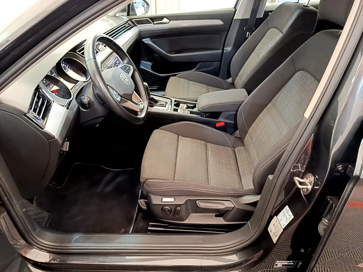 Intérieur avant droit de la Volkswagen Passat gris foncé, montrant sièges tissu et volant cuir multifonctions.