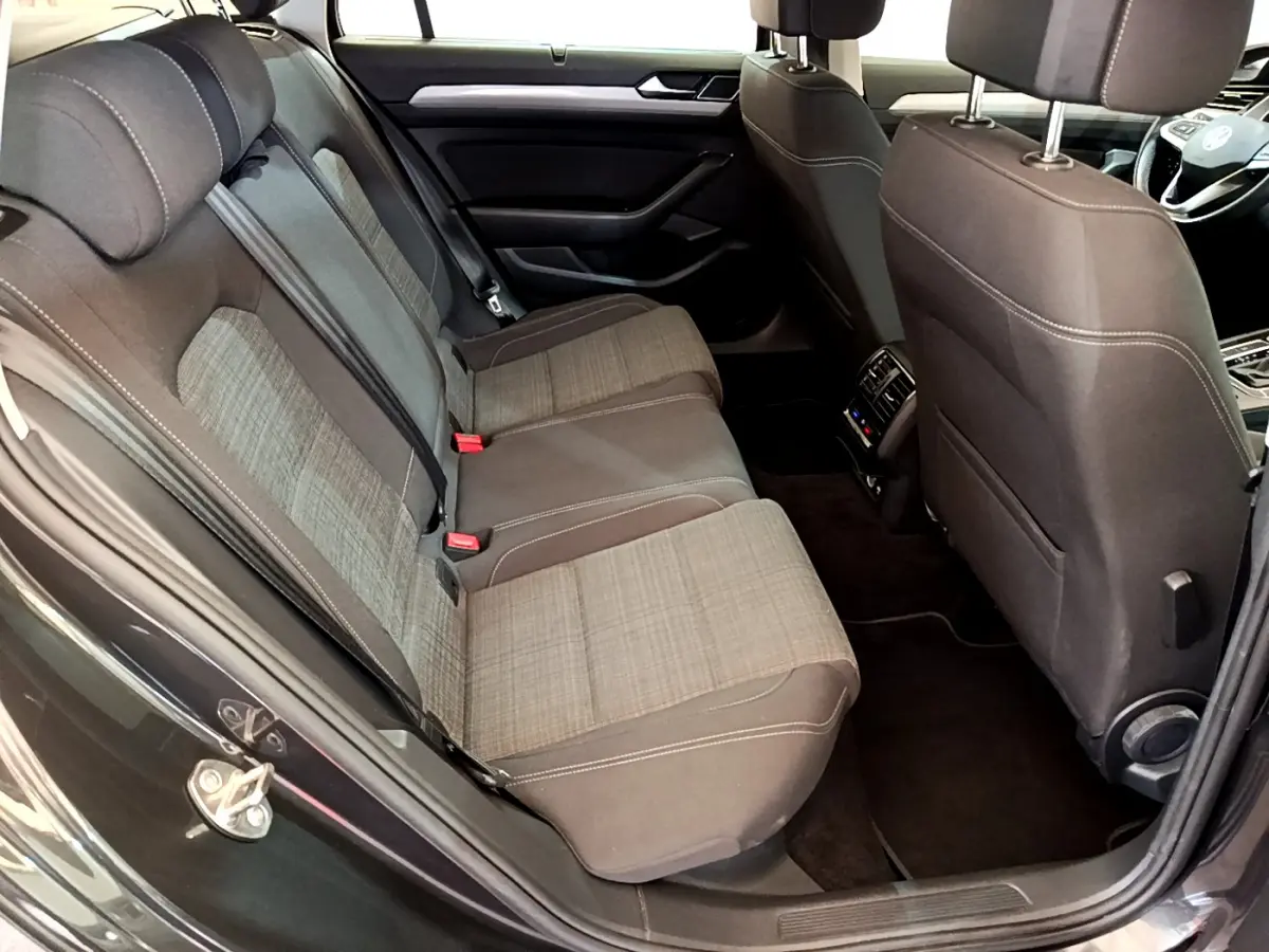 Vue intérieure arrière côté gauche d'une Volkswagen Passat gris foncé, sièges tissu bicolore avec coutures contrastées.