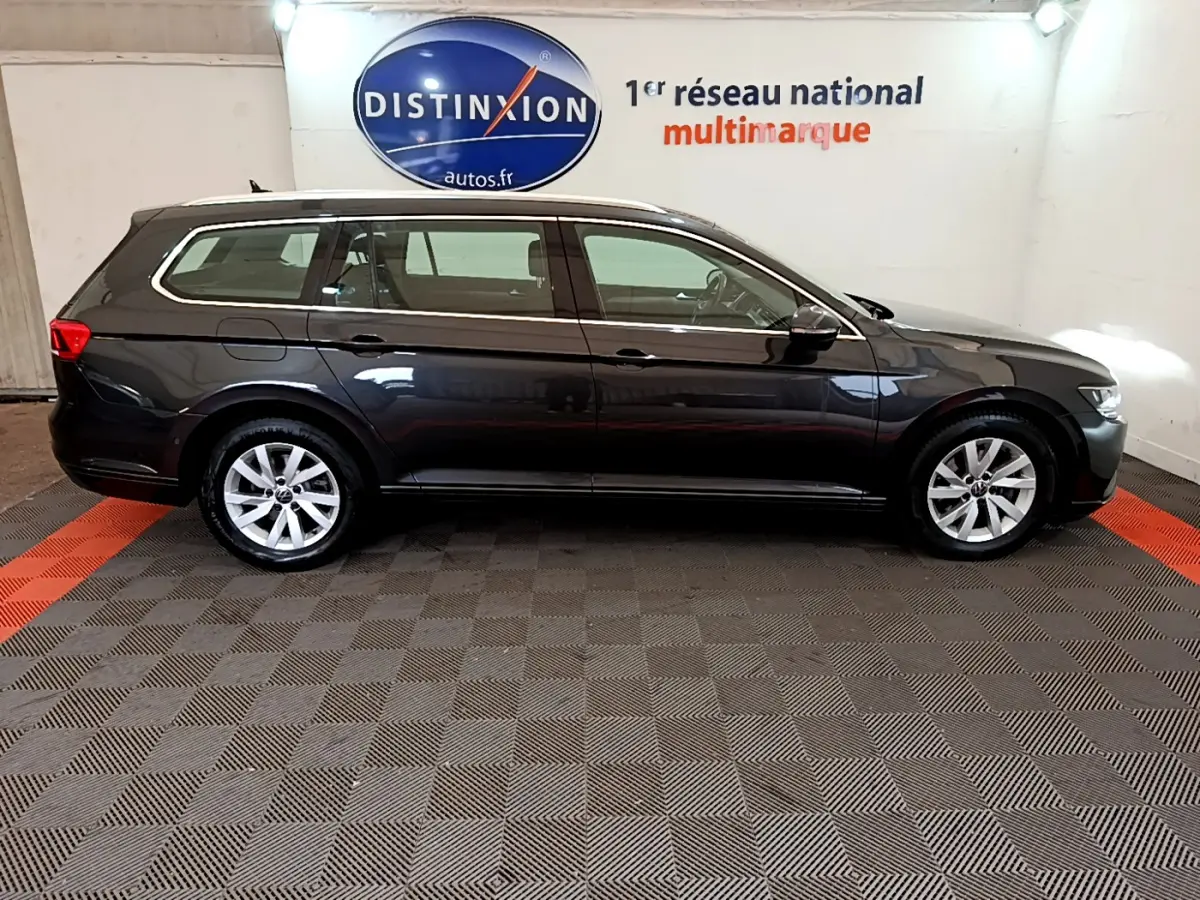 Profil côté droit d'une Volkswagen Passat break gris foncé 2021, stationnée en intérieur sur sol damier.