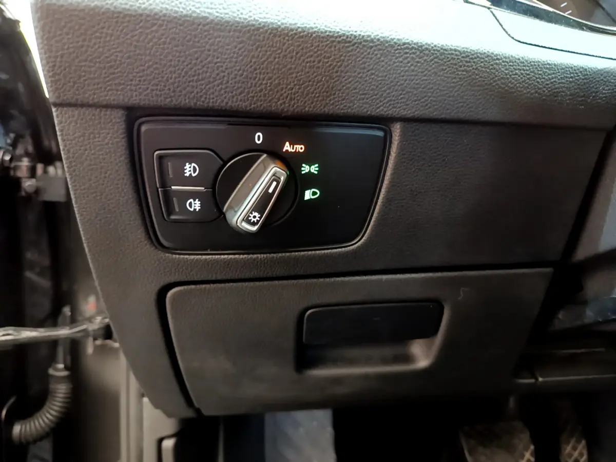 Gros plan sur le bouton de commande des phares dans l'habitacle gris foncé d'une Volkswagen Passat 2021.