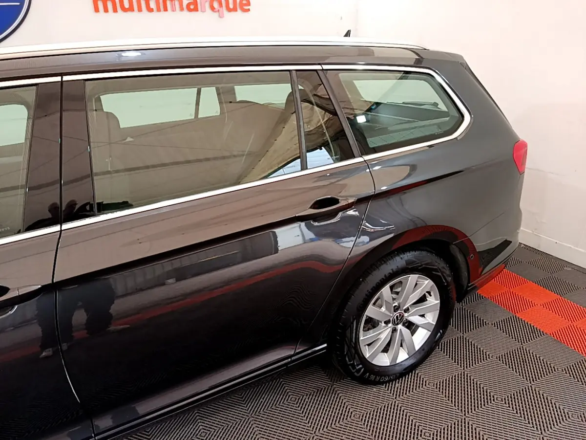 Vue latérale côté droit d'une Volkswagen Passat gris foncé break, mettant en valeur la roue arrière et les vitres teintées.